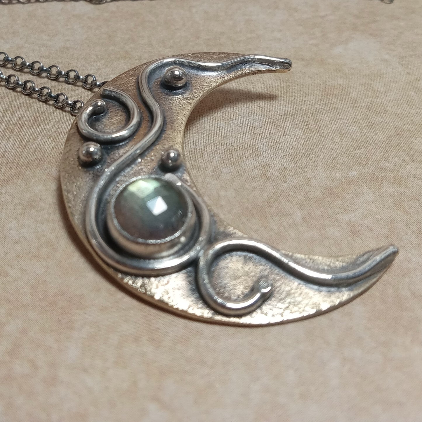 Mixed Metal Moon Necklace – Faceted Labradorite in Bronze and Argentium Silver photo on beige background.