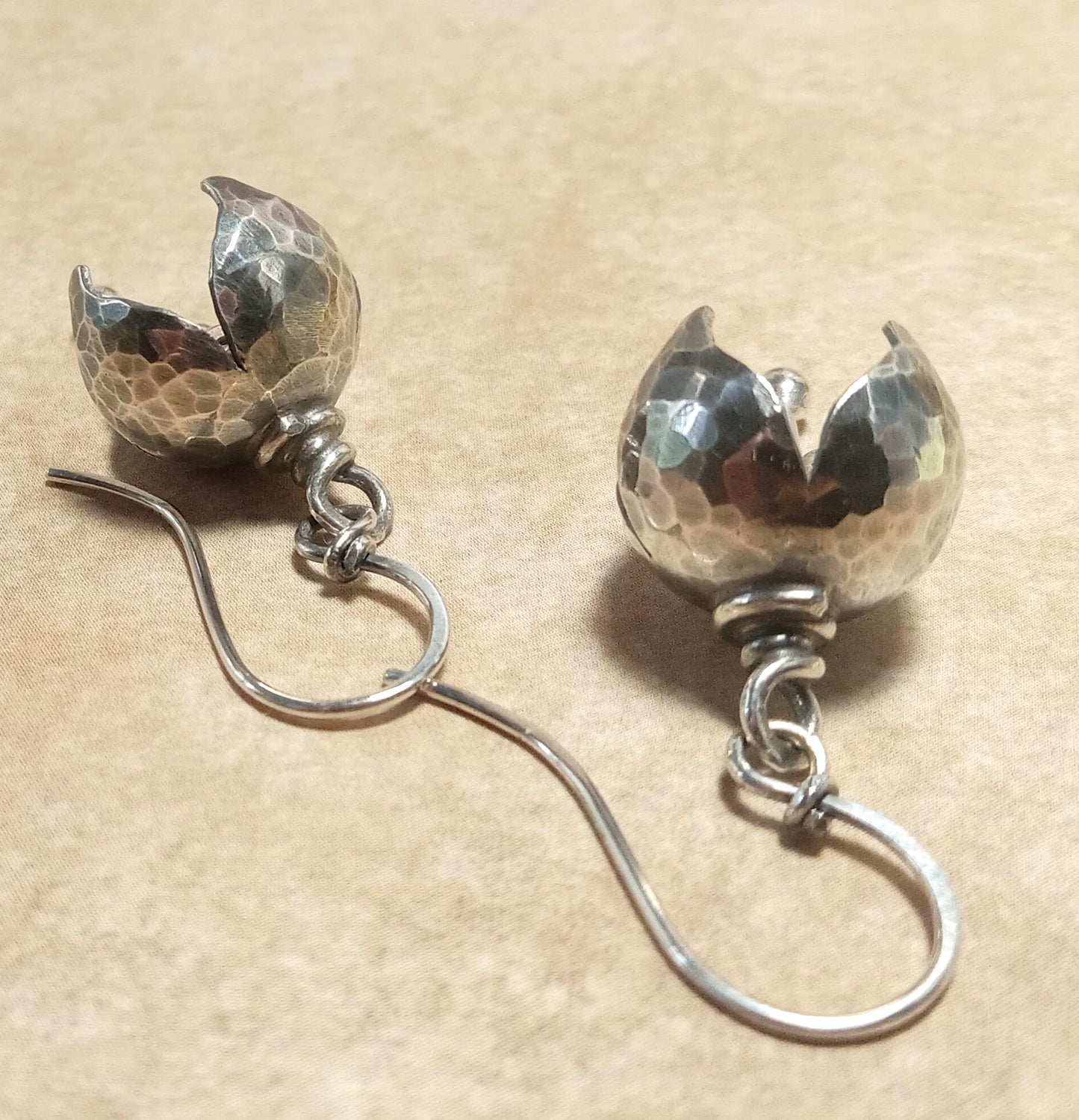 Pair of tinkling bell flower sterling silver earrings on a beige background