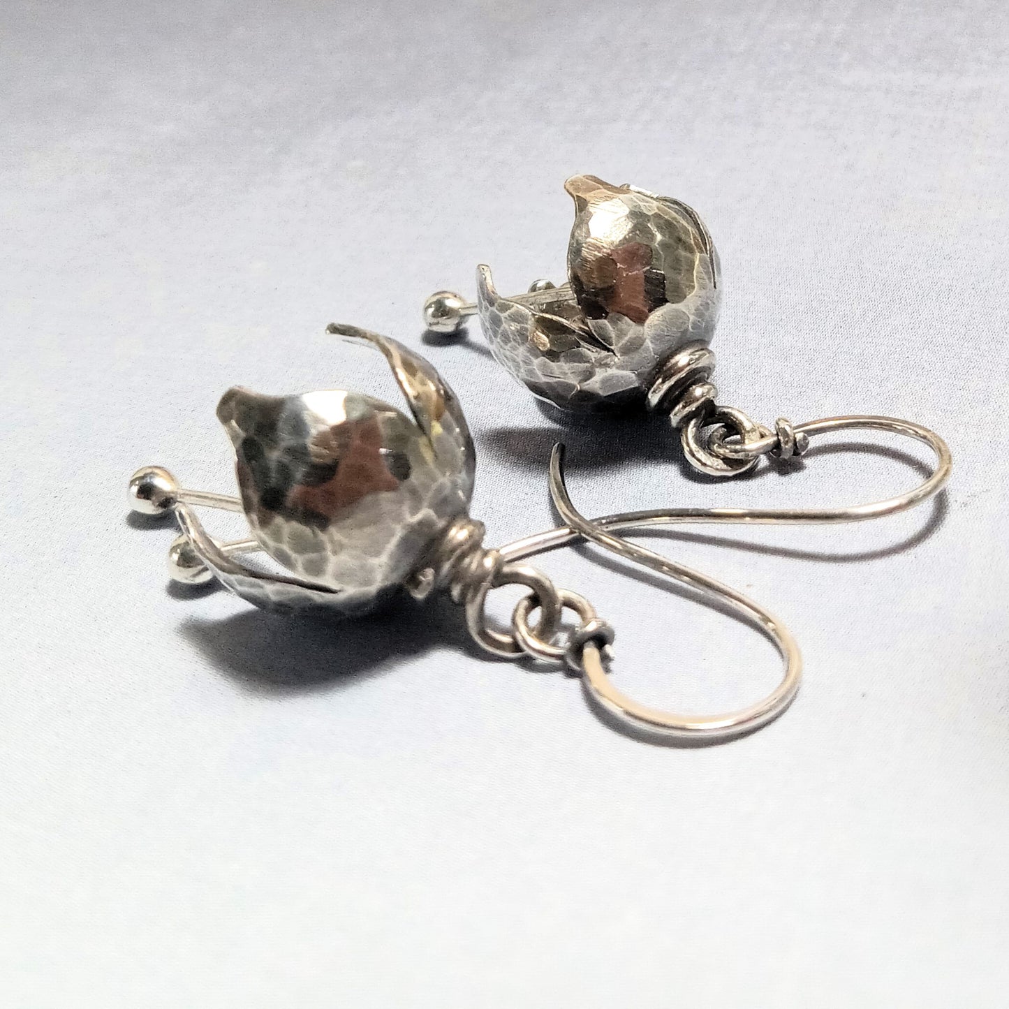 Pair of sterling silver bell shaped earrings on a light gray background.