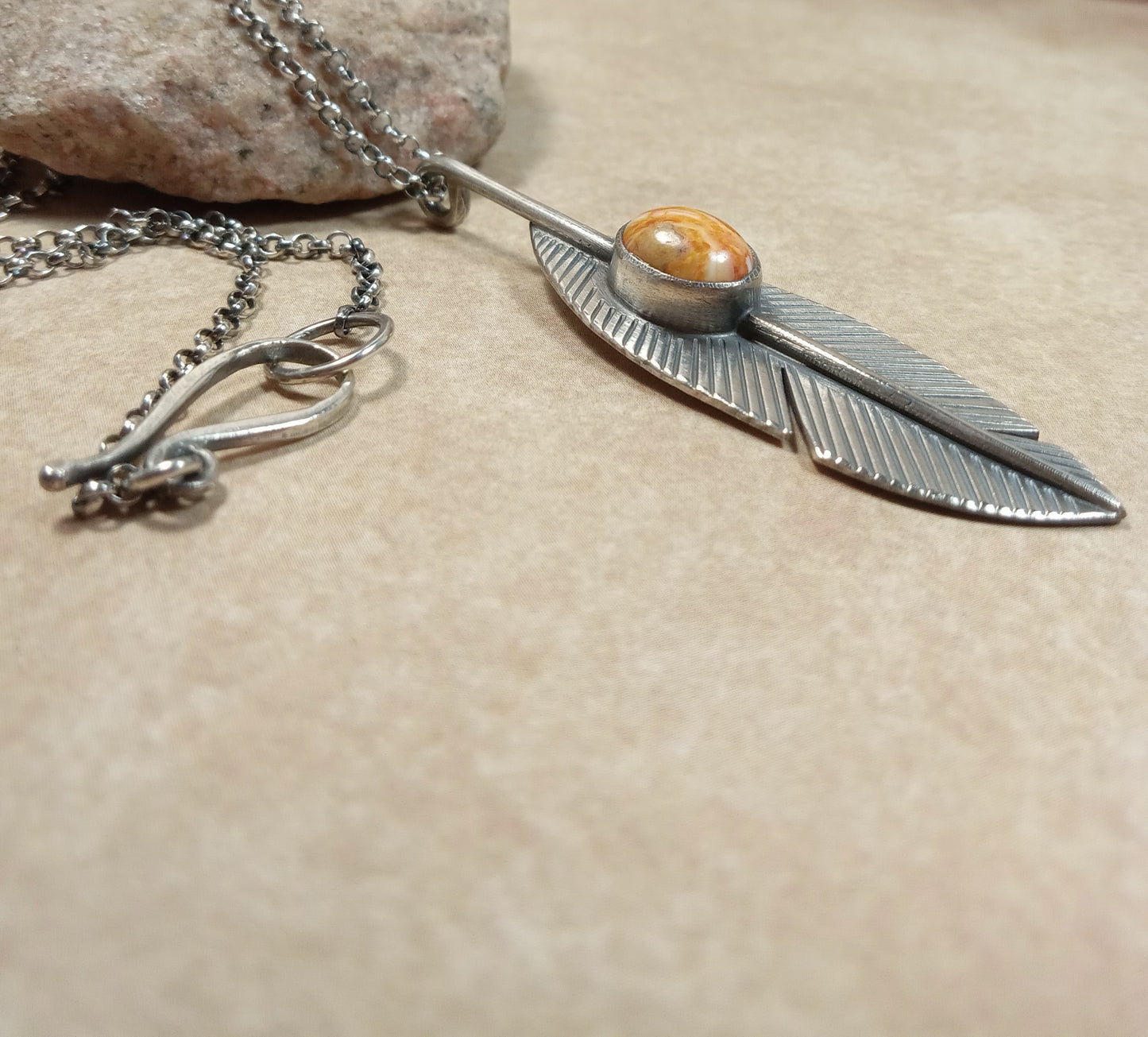 Southwest-inspired feather necklace in Argentium silver with spiny oyster cabochon, SS chain, handmade findings rock in background.