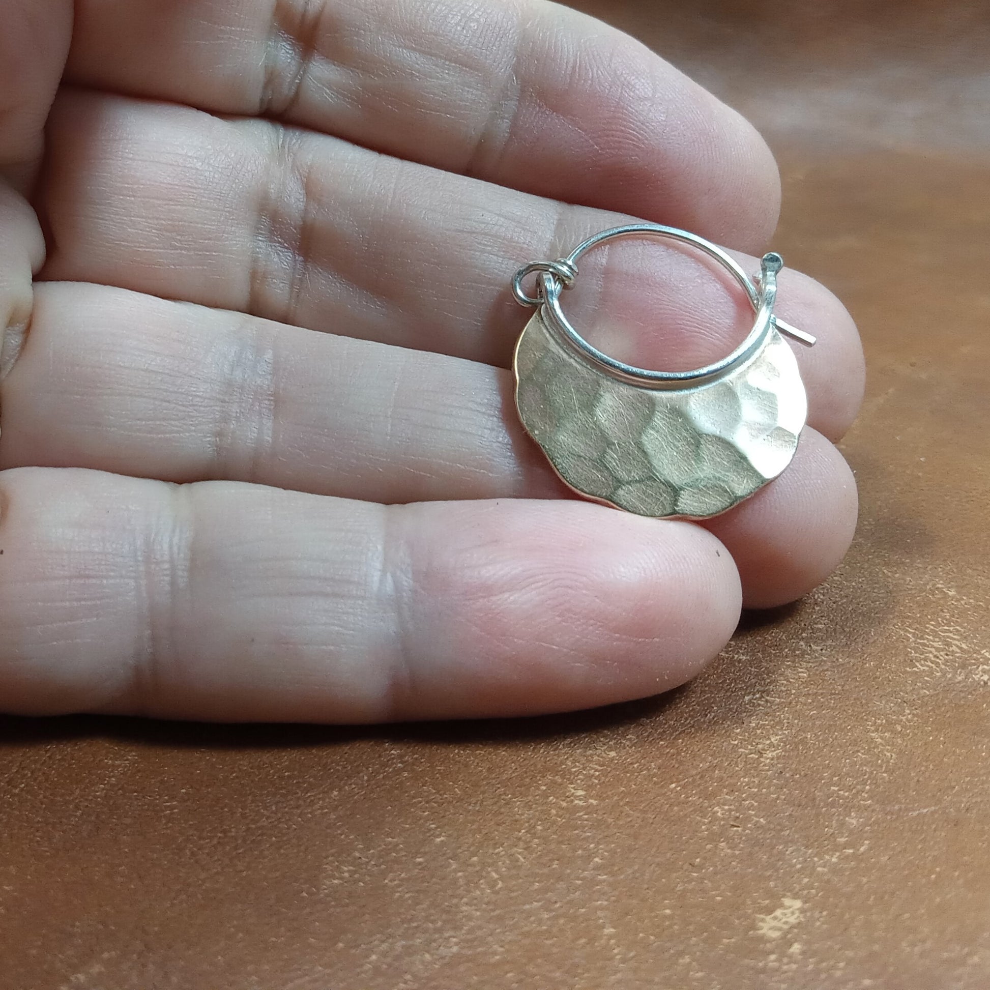 Small bronze crescent hoops with SS ear wires photographed in hand on brown background.