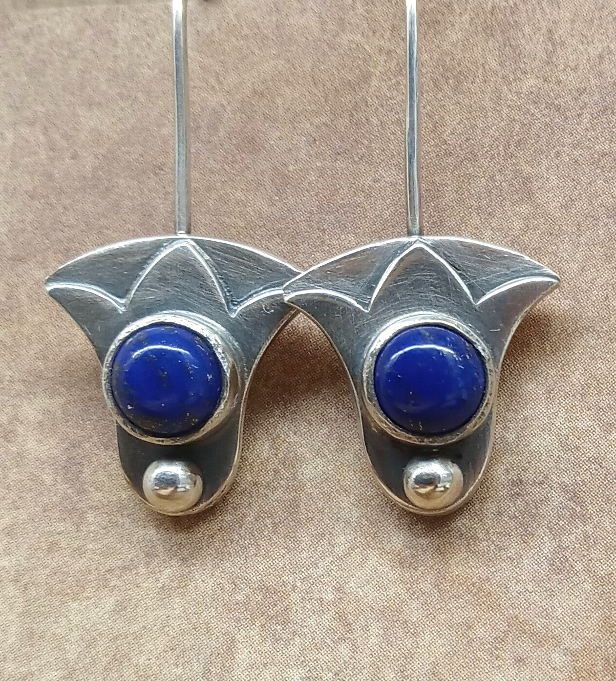 Close-up of Egyptian lotus earrings with lapis lazuli cabochons in Argentium silver.