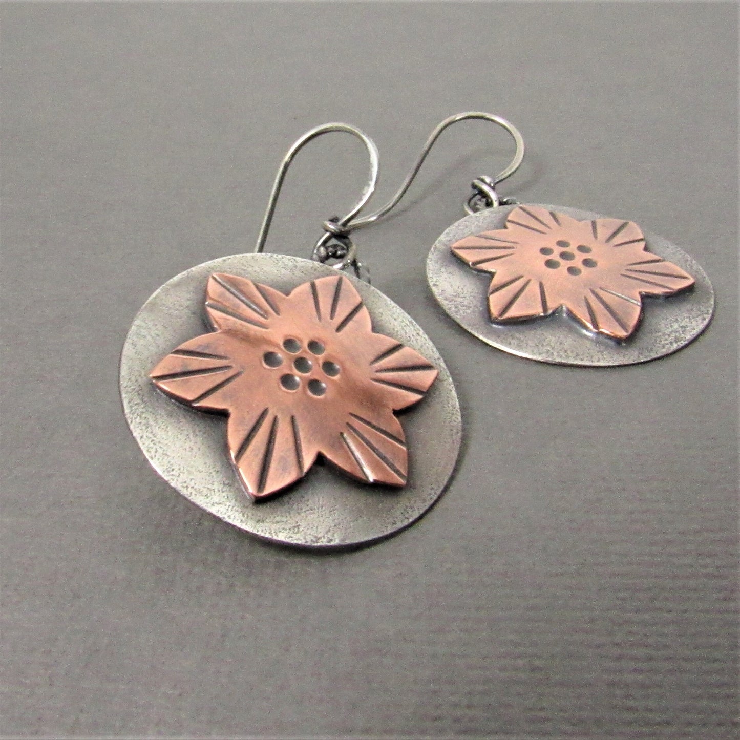 Pair of earrings with floral designs on a gray background