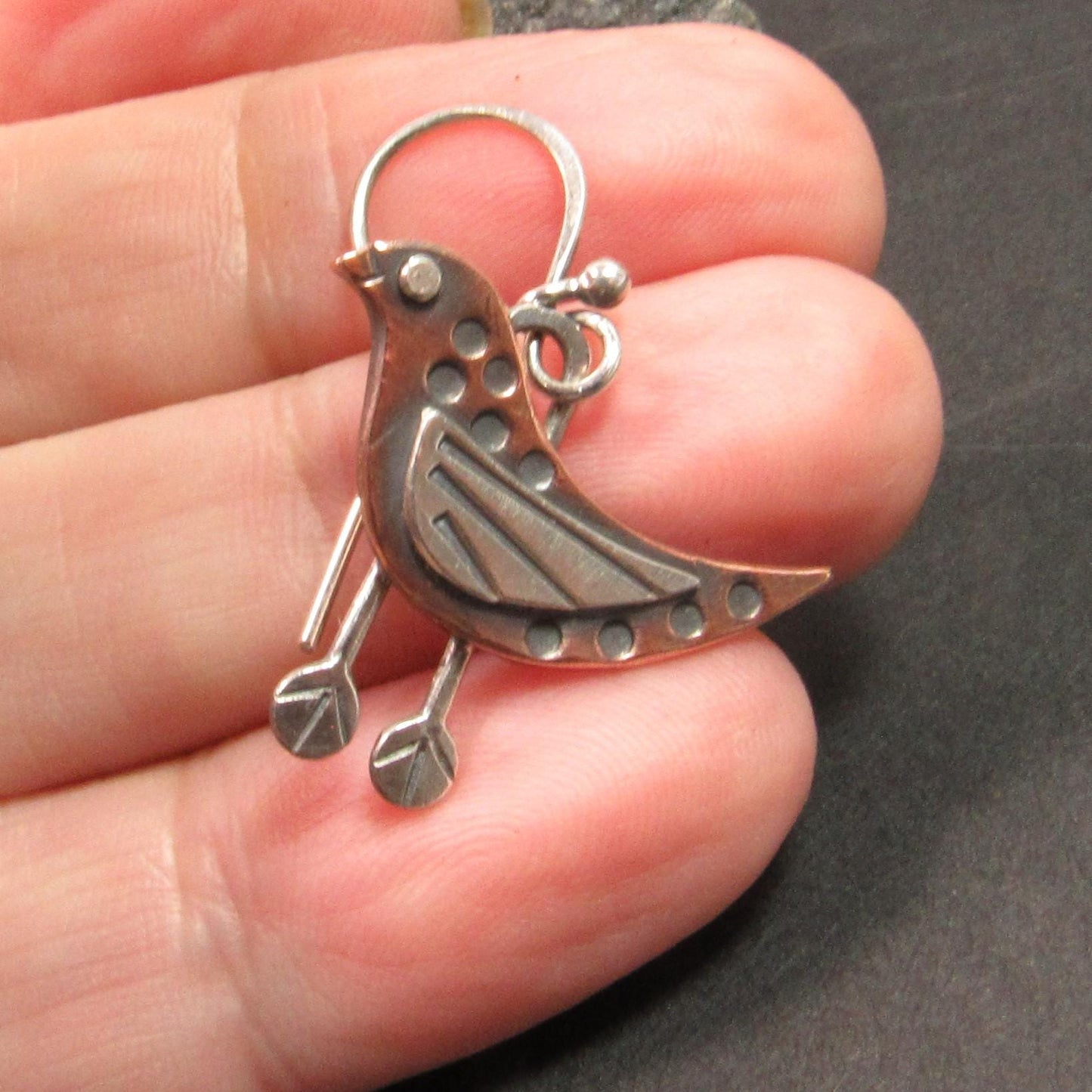 Artisan bird earrings in mixed metals with riveted accents and oxidized finish, perfect for nature lovers. Earring in hand.