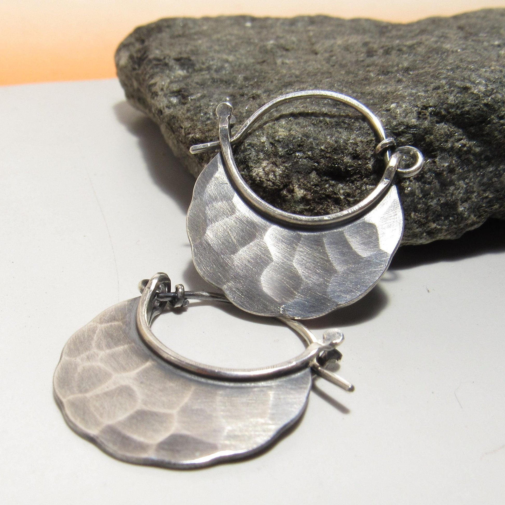 Small hammered Silver hoop earrings with oxidized finish on rock background