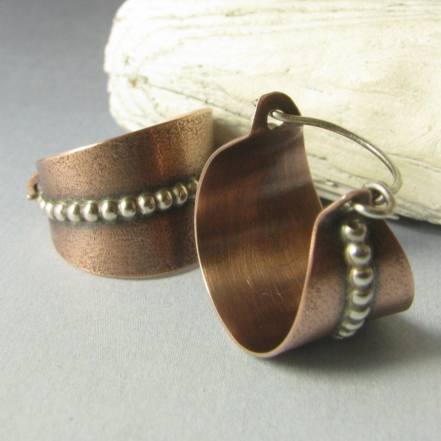 Copper earrings with silver bead detailing on a gray background