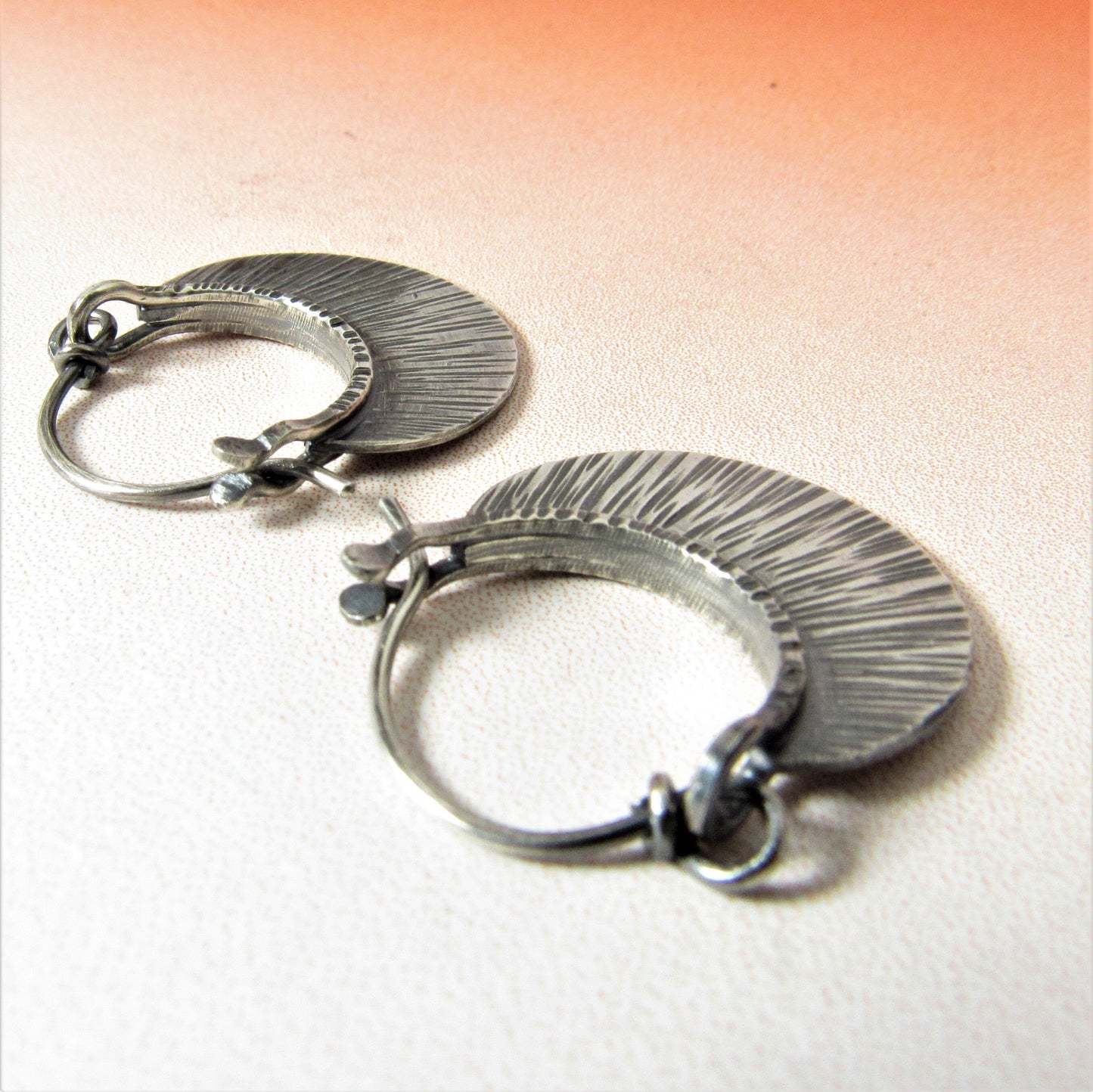 Small SS hoop earrings with friction clasp on orange background.