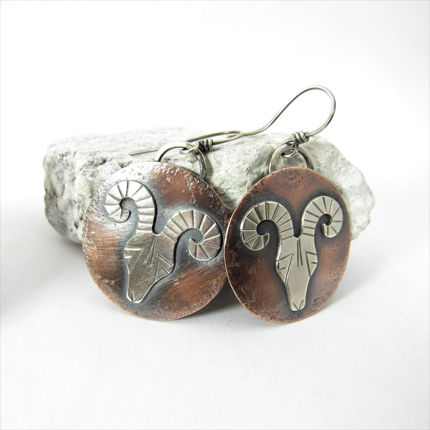 Argentium silver and copper rams head earrings on white background.