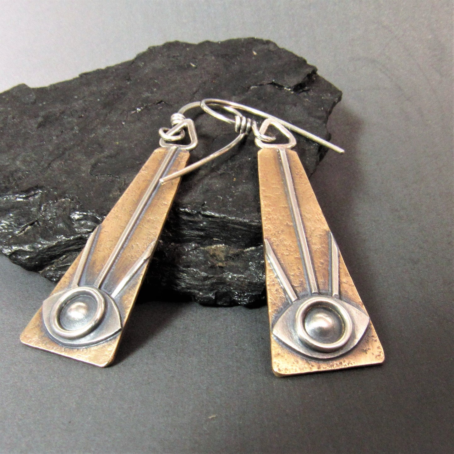 mixed metal all seeing eye earrings with rock and dark background