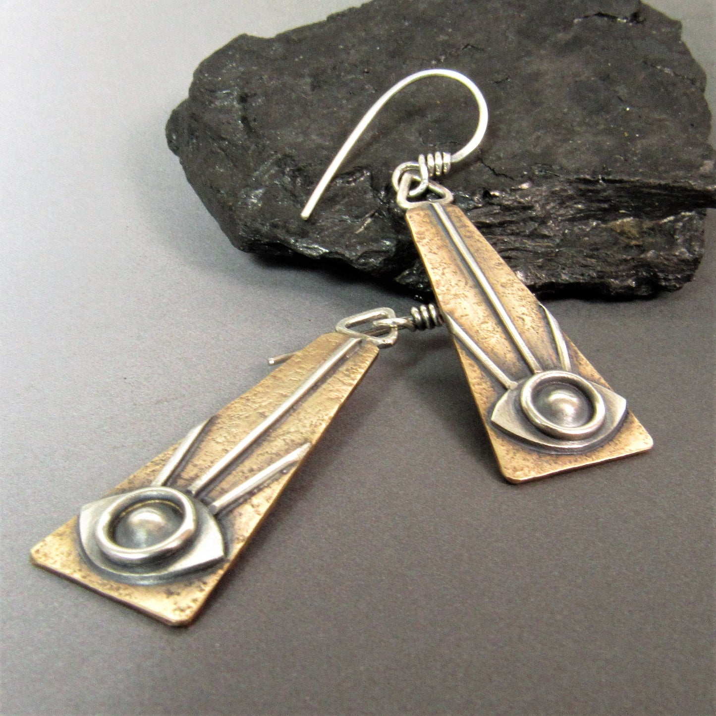 Angled close-up showing textured bronze and silver eye motif with radiating line