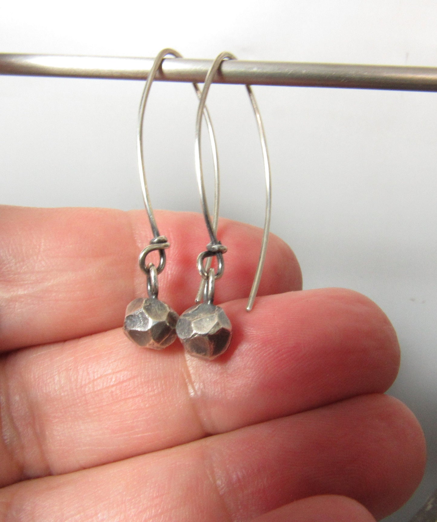 SS faceted Nugget earrings on long ear wires, photographed in hand.