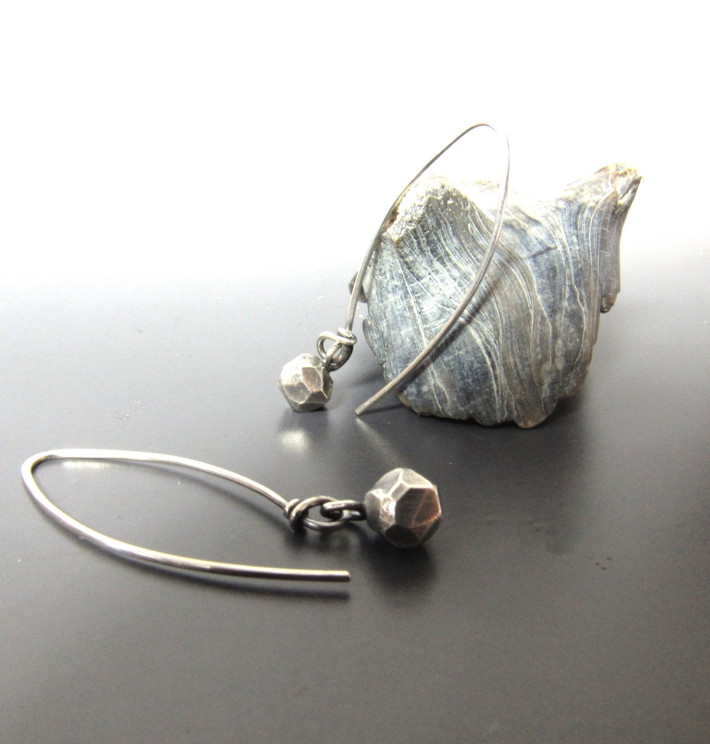 Faceted nuggets of argentium silver, long ear wires, photo against shell on grey background.