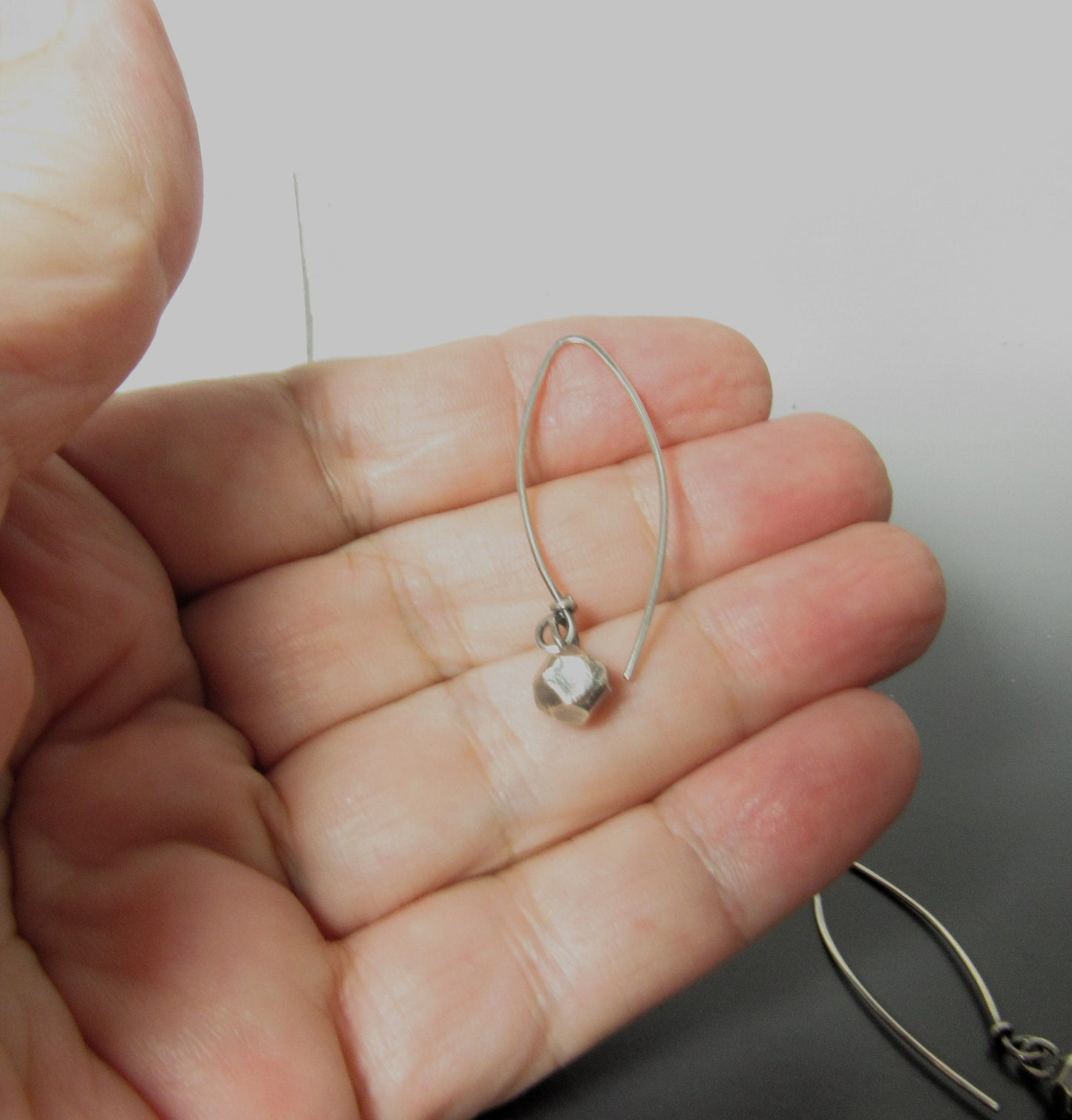 Photo in hand of SS nugget earrings, hand faceted on long ear wires.