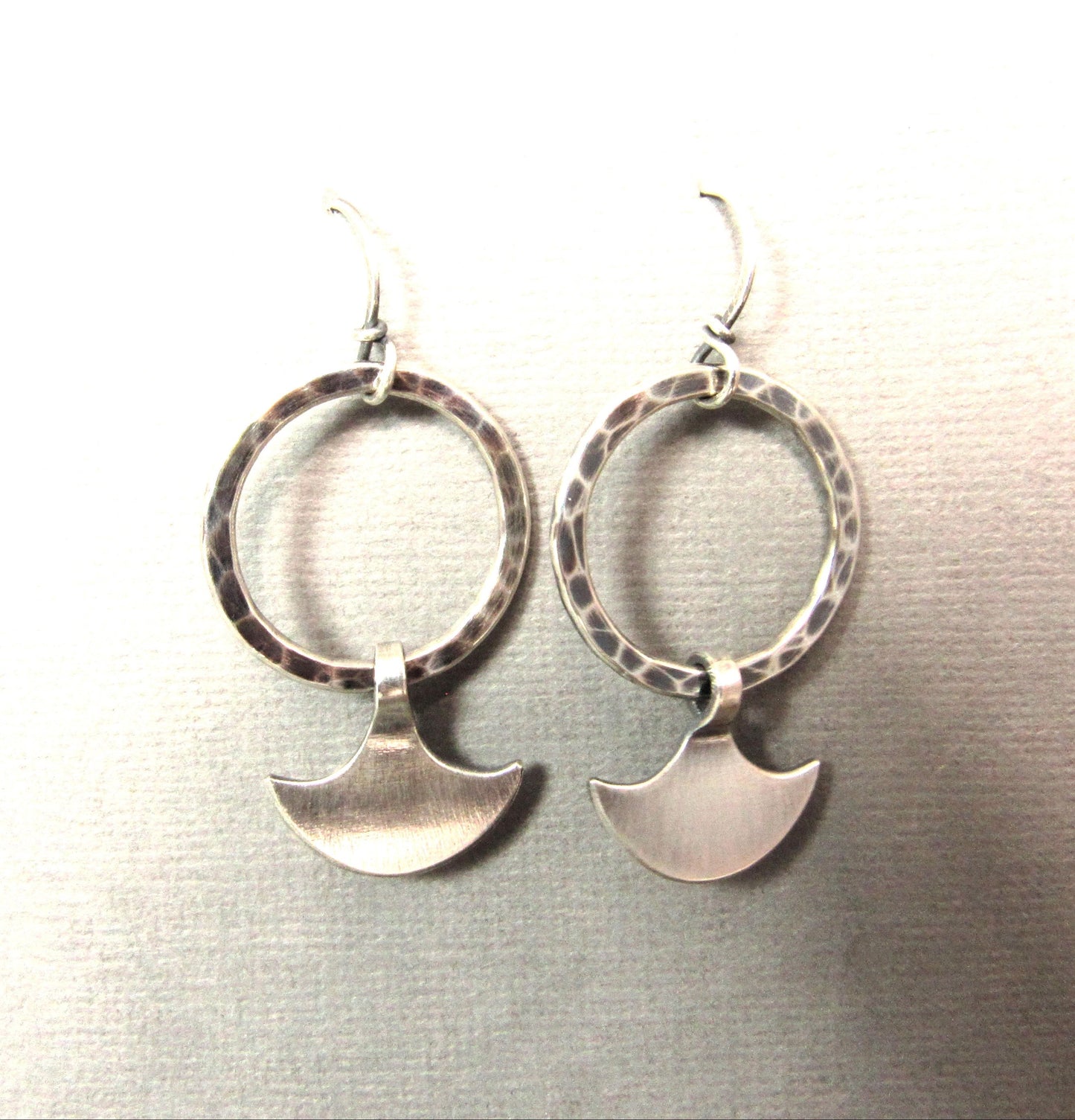Durga silver hoop dangles suspended on grey paper.