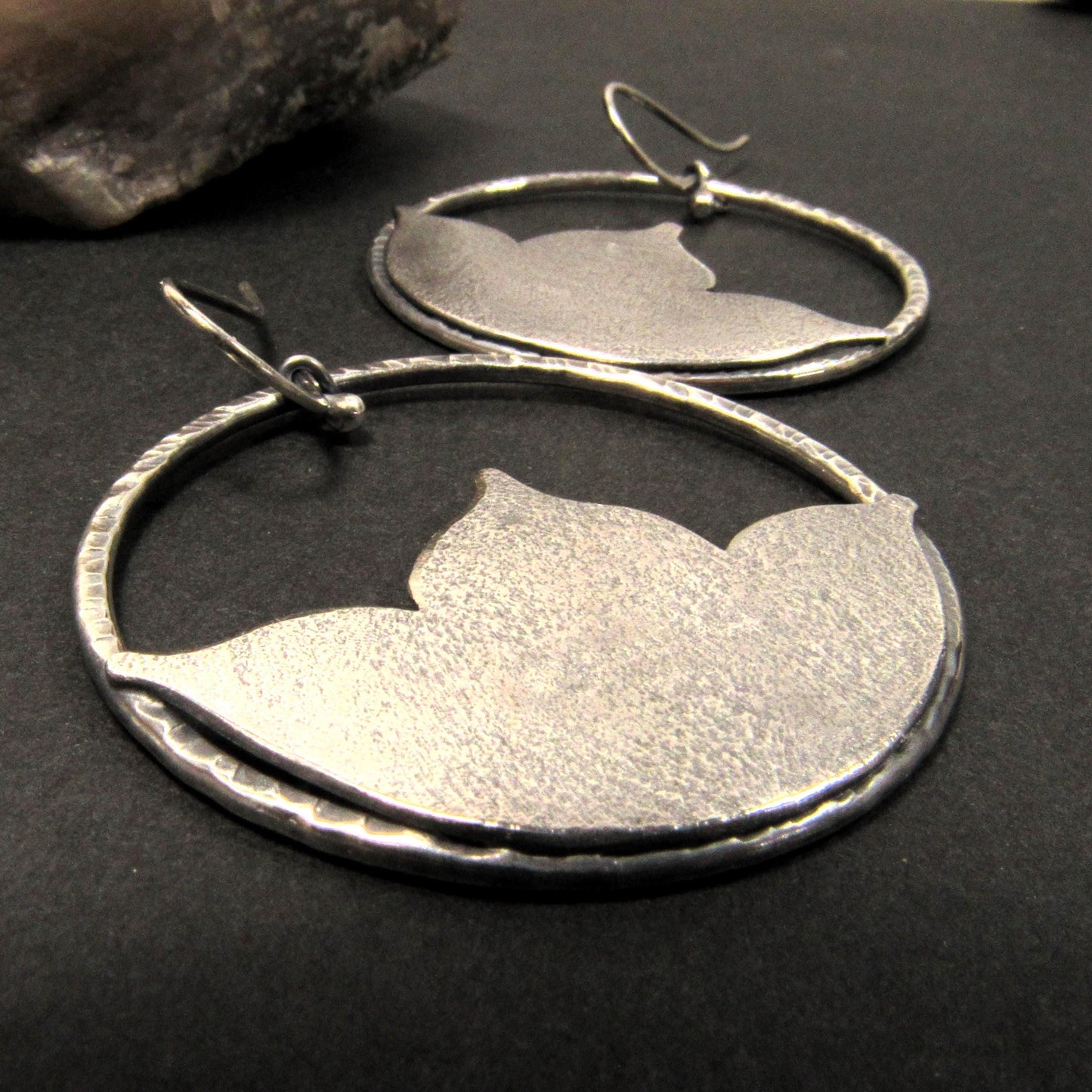 Large argentium silver lotus earrings on black background.