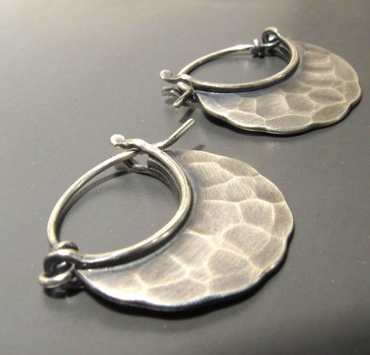 Pair of small hammered silver hoop earrings on a gray background