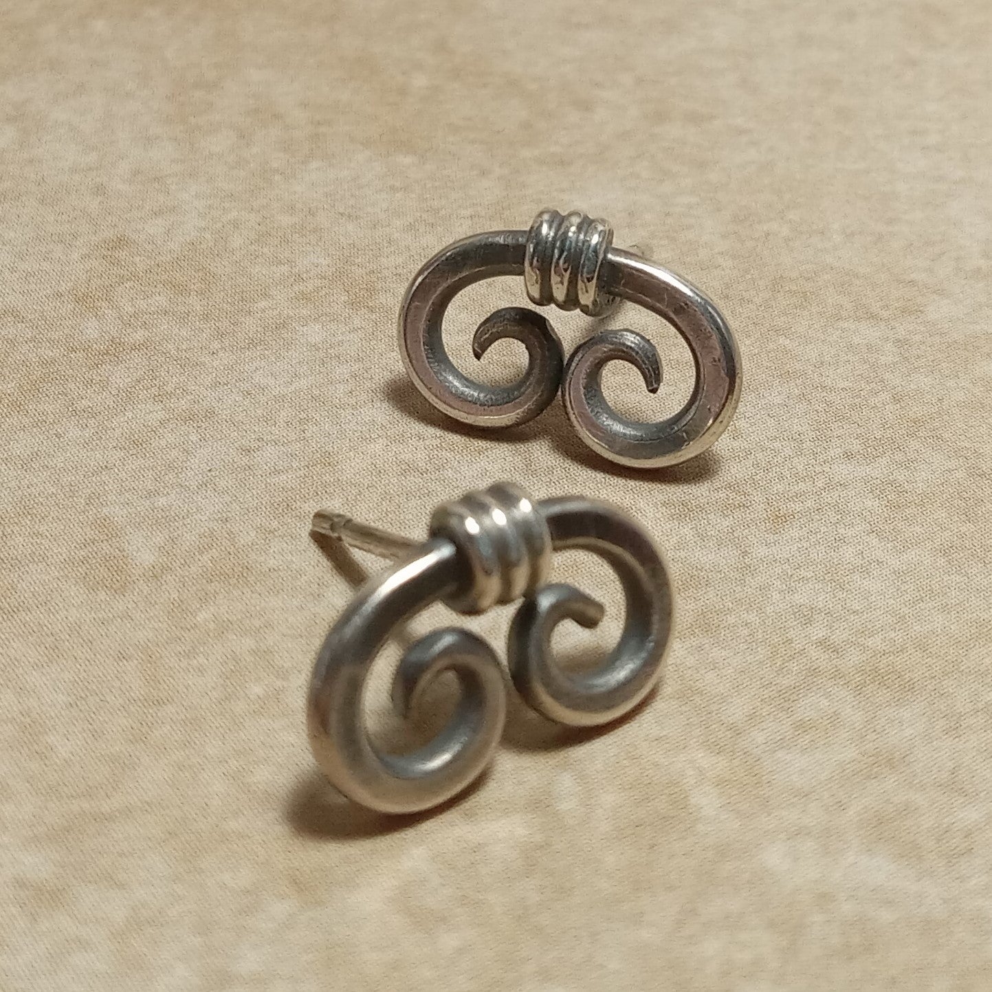 Small handcrafted sterling silver spiral stud earrings with a modern, minimalist design inspired by ancient Egyptian motifs. Made from thick silver wire with standard sterling silver posts and ear nuts. Displayed on a neutral background