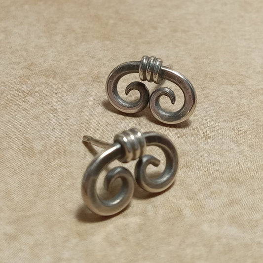 Small handcrafted sterling silver spiral stud earrings with a modern, minimalist design inspired by ancient Egyptian motifs. Made from thick silver wire with standard sterling silver posts and ear nuts. Displayed on a neutral background