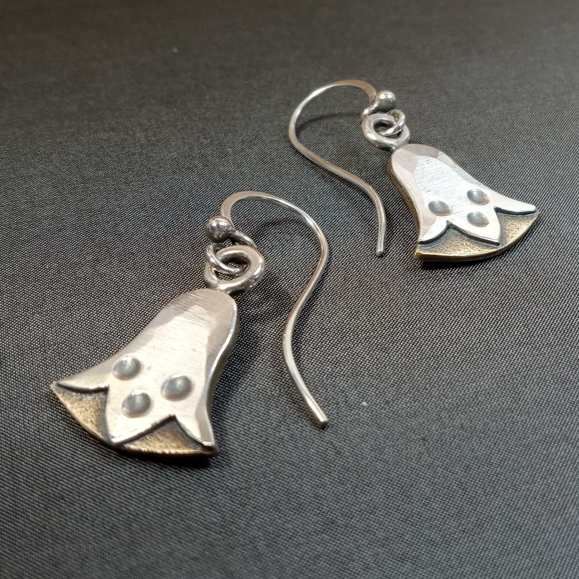 Bronze and argentium silver egyptian lotus earrings by Mocahete on a dark gray background