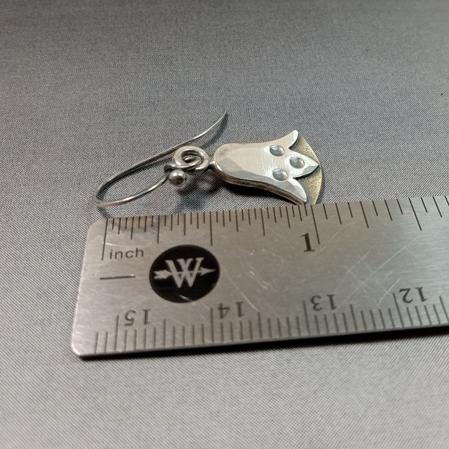 Mixed metal lotus flower earrings on a metal ruler for scale.
