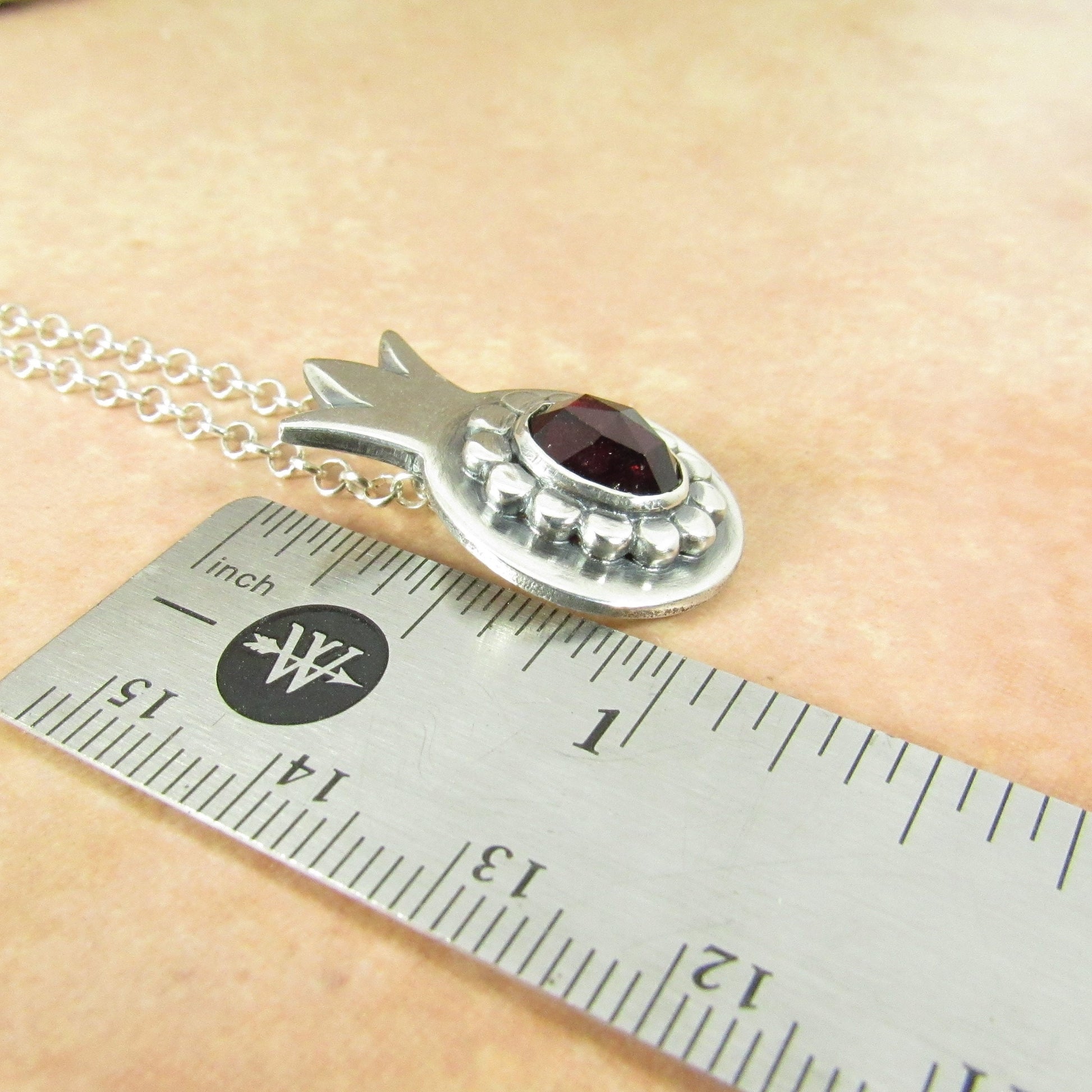 Argentium Silver pomegranate pendant with a garnet gemstone  shown
 with a ruler for scale. 