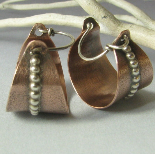 Copper hoop earrings with bead detailing on a branch background