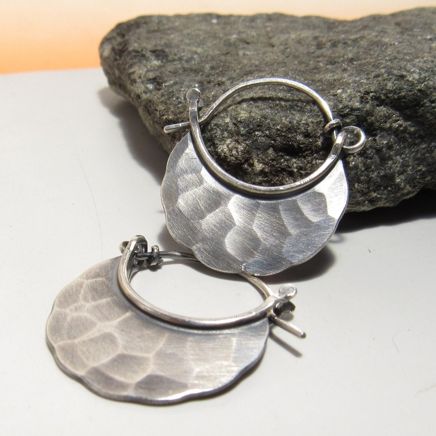 Small hammered Silver hoop earrings with oxidized finish on rock background