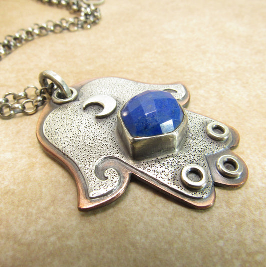 Front view of handcrafted Hamsa necklace in copper and sterling silver with hexagon lapis lazuli centerpiece and crescent moon detail