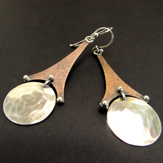Architectural artisan earrings with Eiffel Tower-inspired detailing, handcrafted in mixed metals by Mocahete. Photo on dark background.