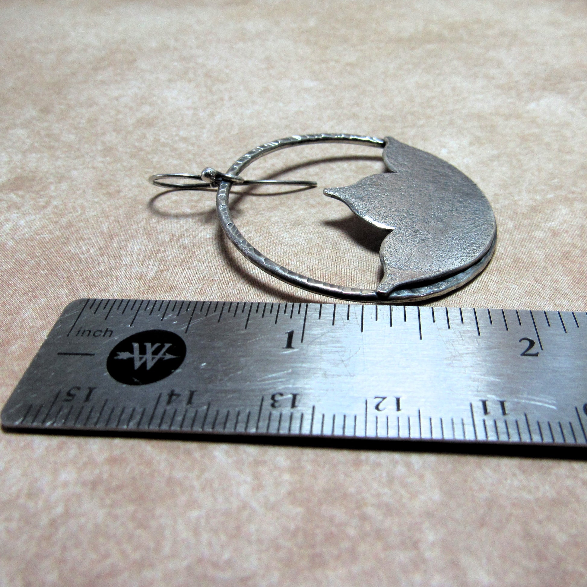SS large lotus shape earrings next to a ruler on a beige surface.