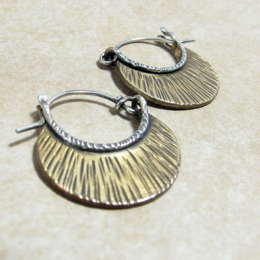 Pair of handcrafted  silver and bronze hoop earrings with latching closure  on a beige background.