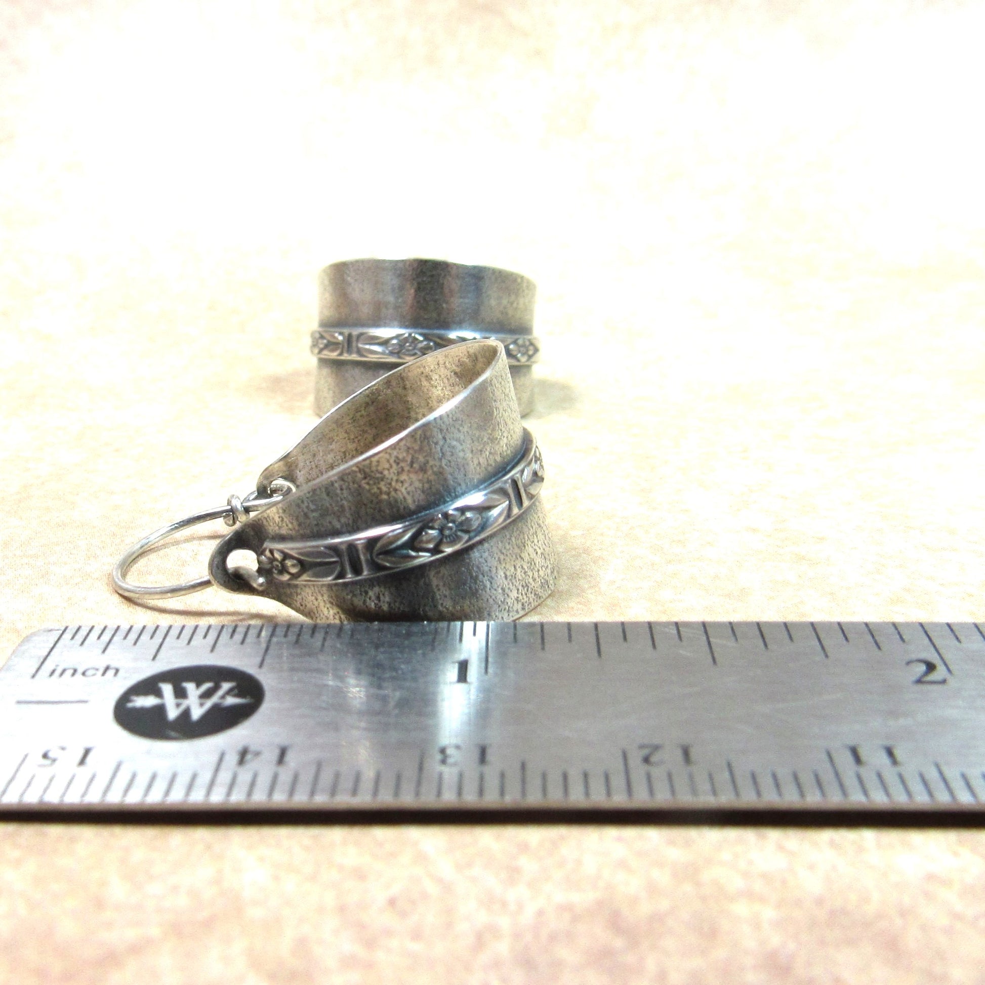 Silver hoop earrings on a ruler for size reference.