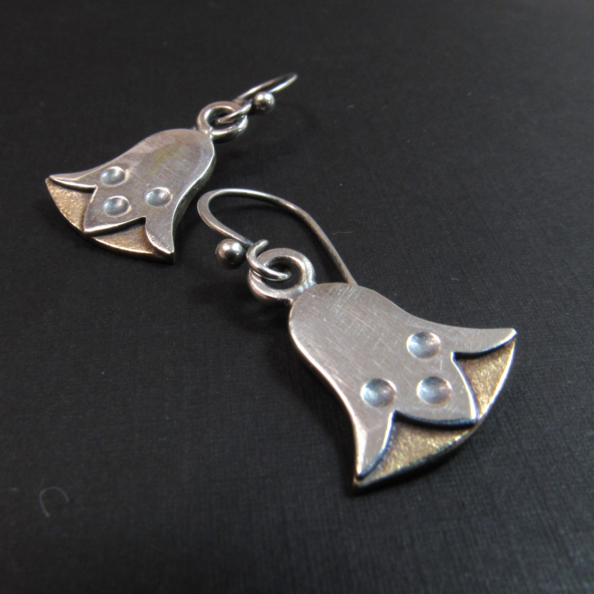 Pair of silver and bronze lotus flower earrings on a black background