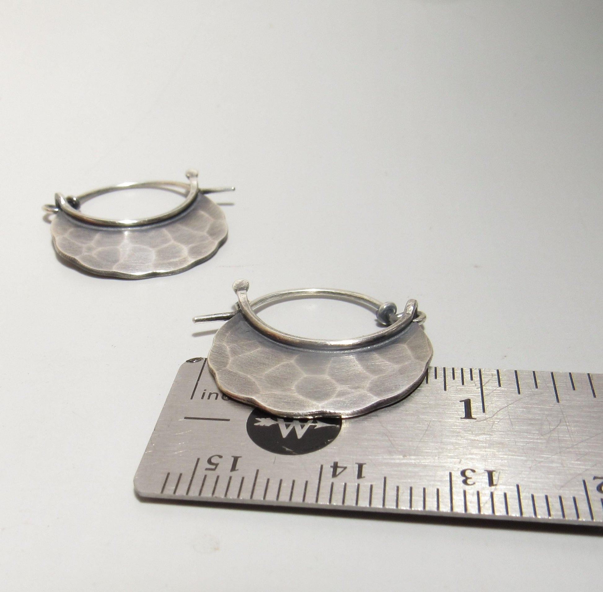 Silver hoop earrings on a ruler for size reference