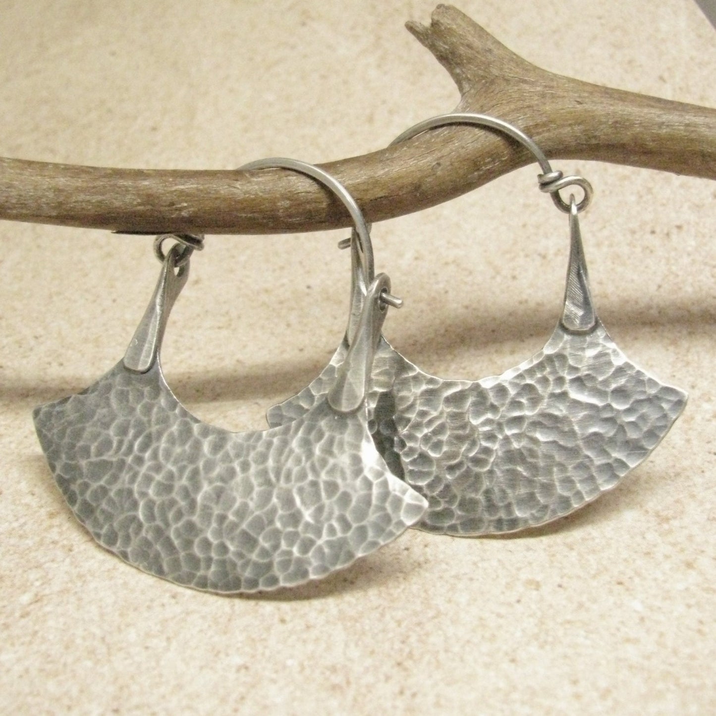 sterling silver hammered hoops by Mocahete displayed against twig and tile background

