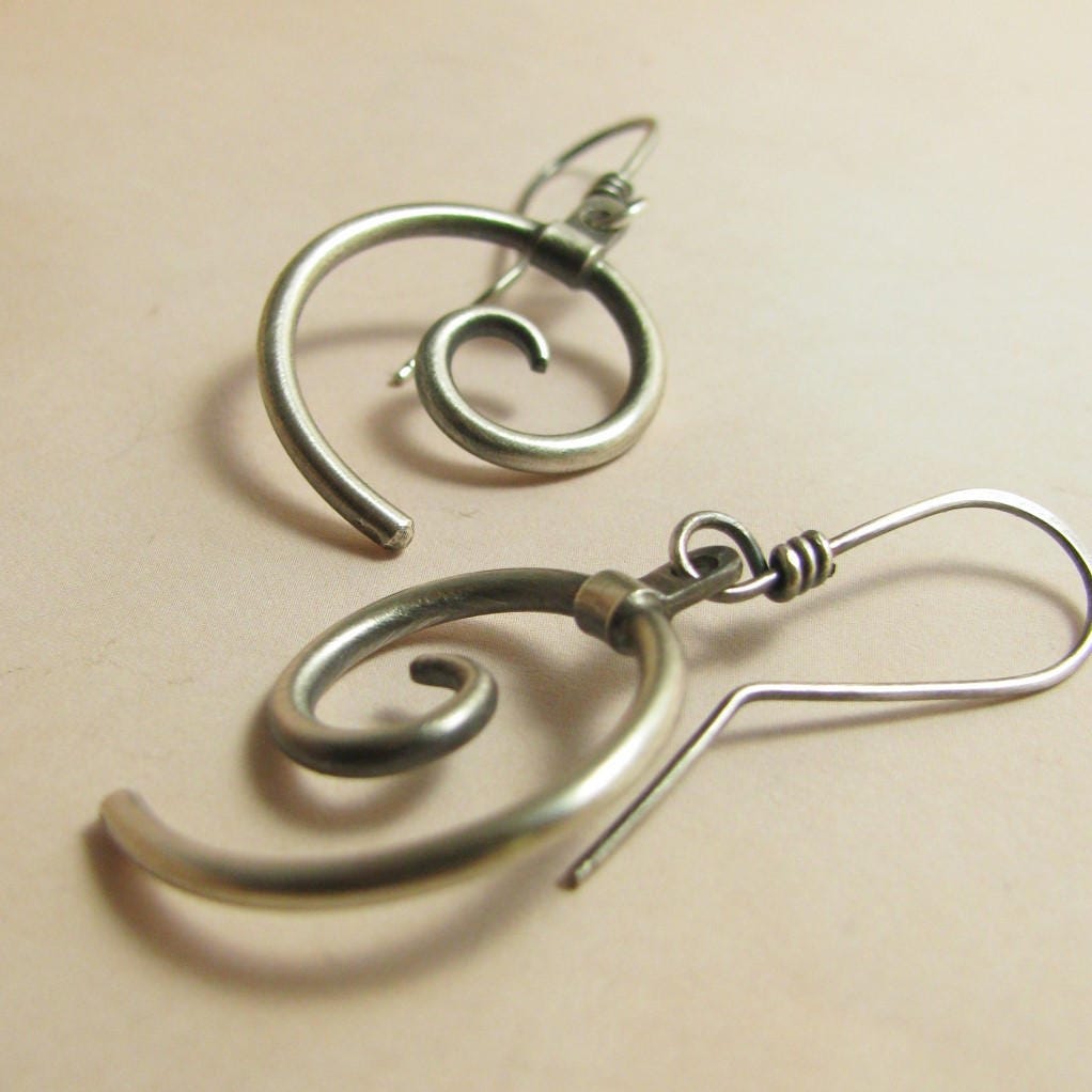 SS spiral earrings on bige background, side view.