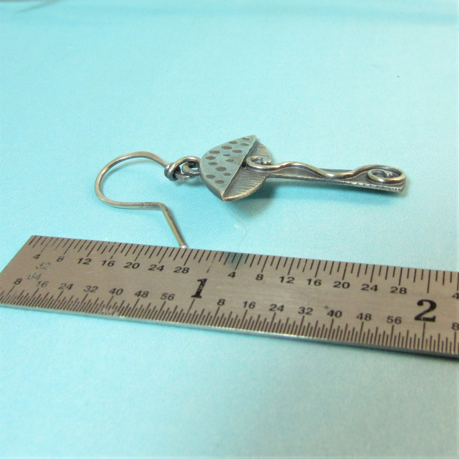 Handmade SS mushroom earrings next to ruler on blue background.