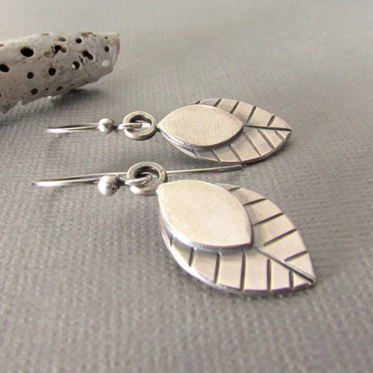 Swingy Argentium SS leaf earrings by Mocahete on grey background with shell.