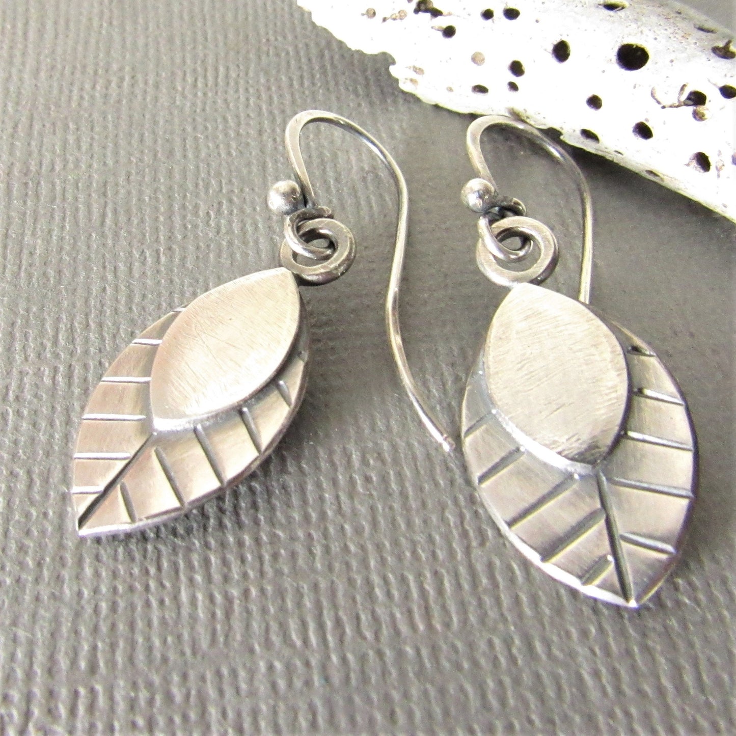 Nature jewelry, leaf earrings, handmade argentium SS dangles photographed on grey background with shell.