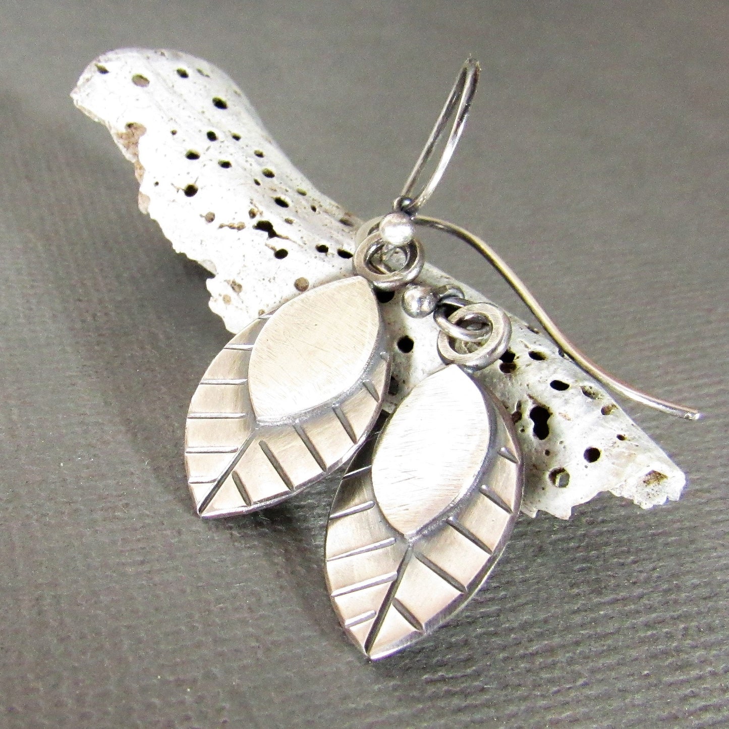 Leaves for your ears, swing SS handmade leaf earrings against shell on grey background.