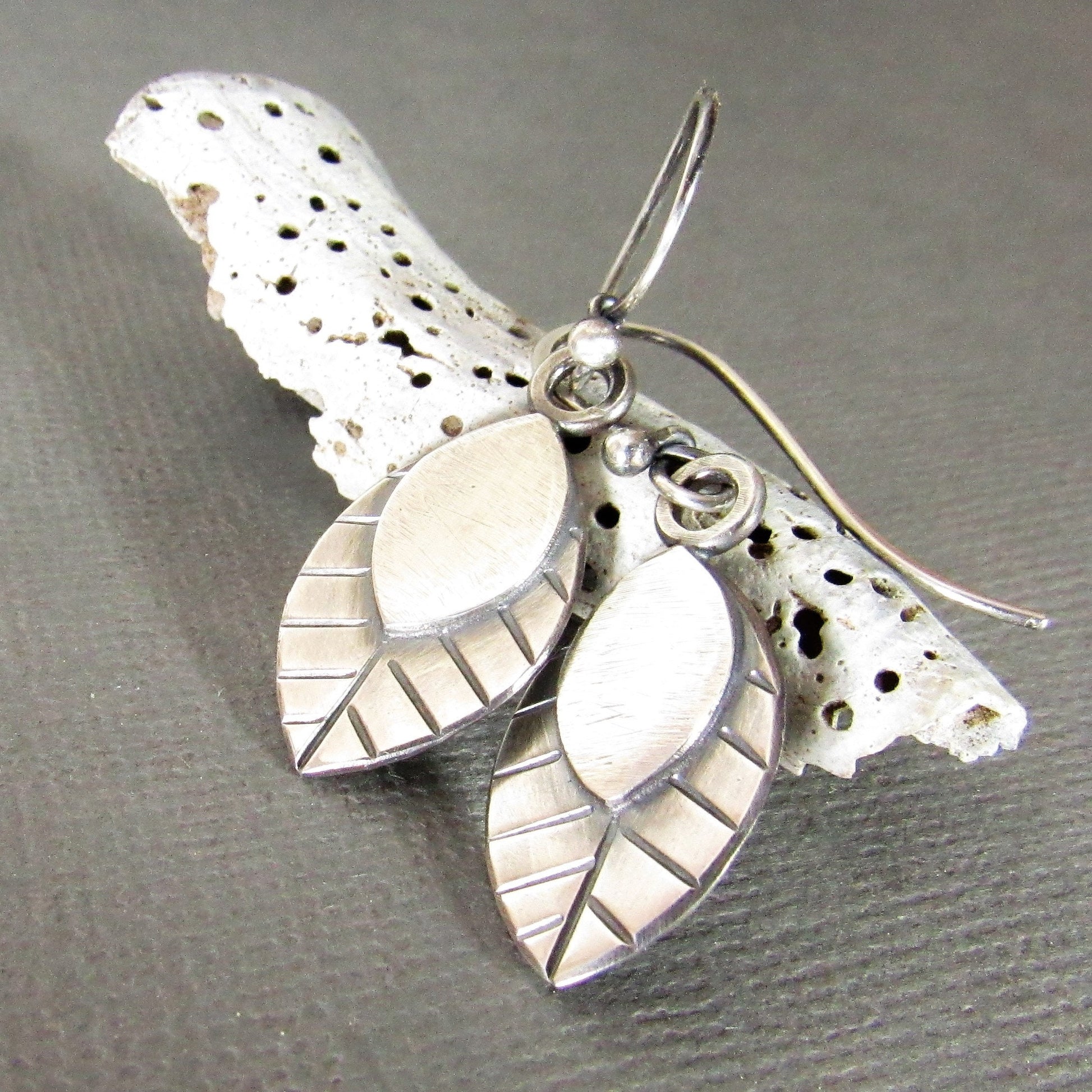 Leaves for your ears, swing SS handmade leaf earrings against shell on grey background.