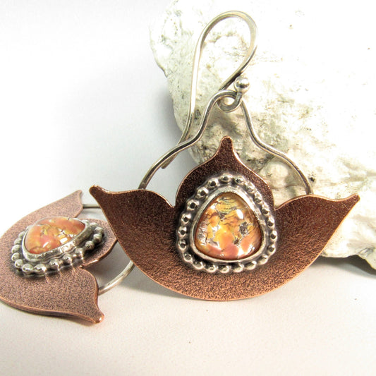 Handcrafted copper and silver lotus earrings with vintage golden pink glass opal cabochons from 1940s Japan, artisan made by Mocahete. Photo on white background with white rock as prop.