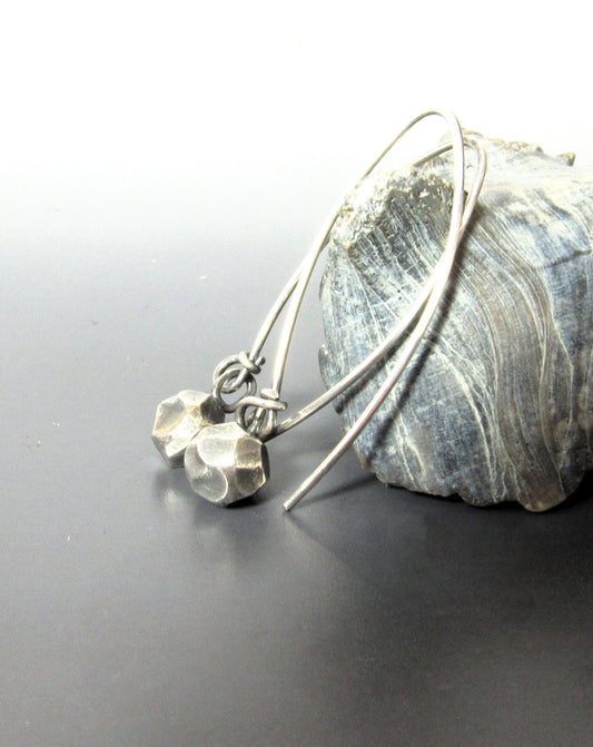 Faceted SS nugget earrings against shell on dark background.