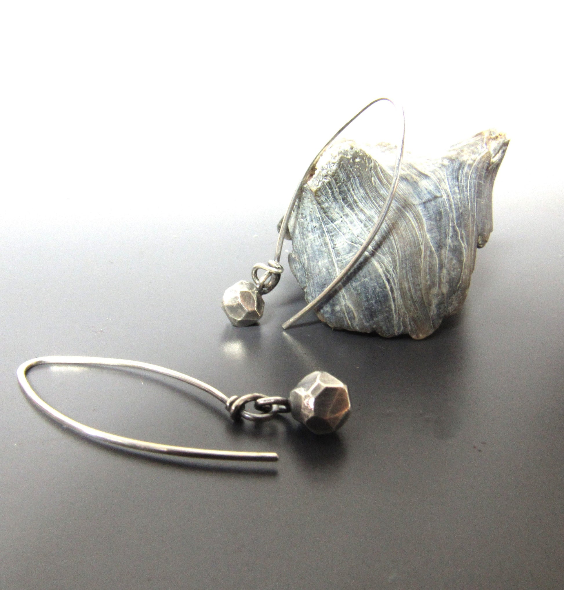 Faceted nuggets of argentium silver, long ear wires, photo against shell on grey background.
