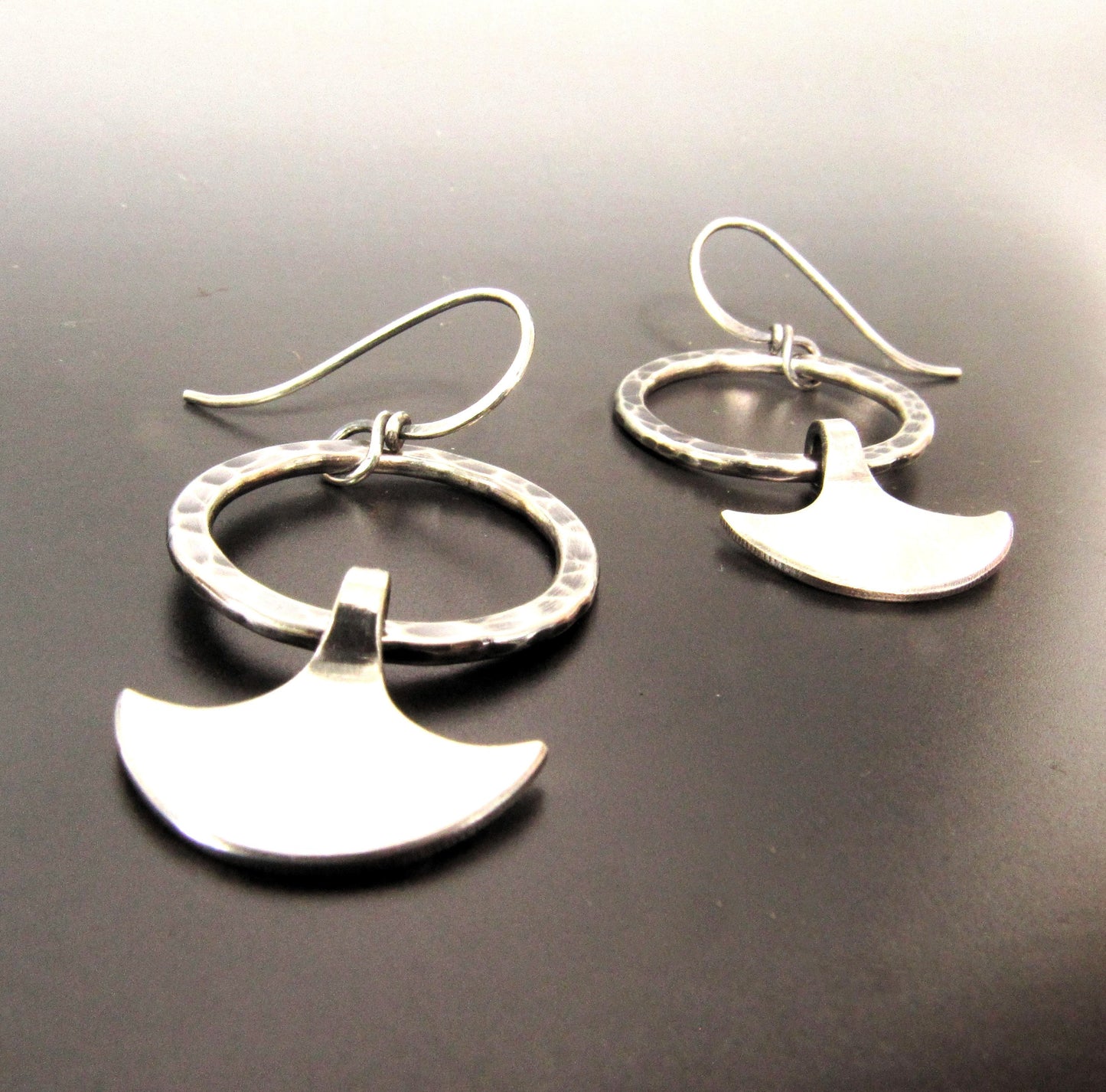 Hammered Argentium silver hoop earrings with oxidized finish and dangling axe blade charms, inspired by goddess Durga.