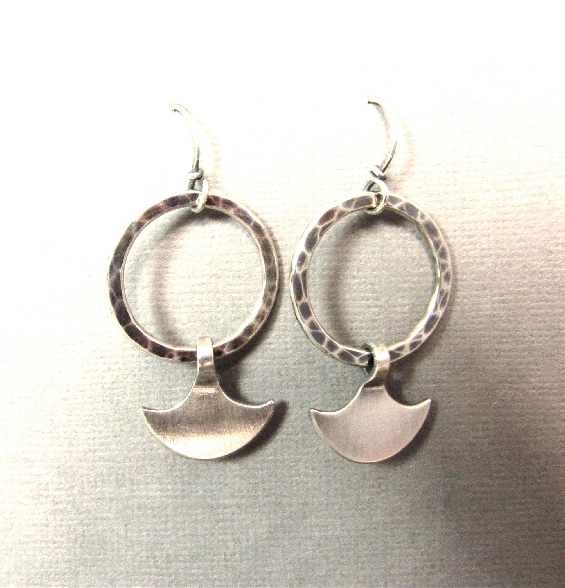 Durga silver hoop dangles suspended on grey paper.