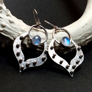 Tribal influenced Argentium silver lotus petal earrings with moonstones. Displayed against white antler on black background.