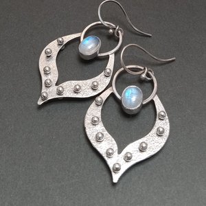 Argentium lotus petal earrings with moonstones. Apx 2" long x 1and 1/8" wide. Displayed on black background.
