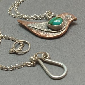 Mixed metal and turquoise bird necklace showing chain and findings. Displayed on grey background.