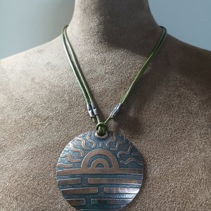 Large copper pendant with adjustable leather cord displayed on mannequin.
